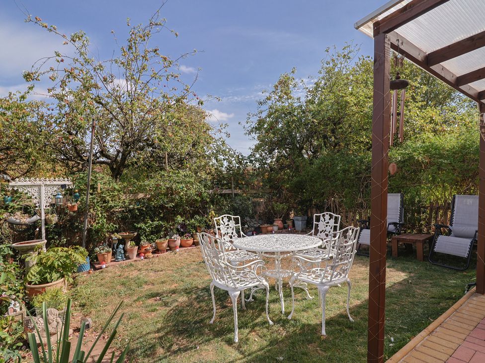 A garden with a table and chairs surrounded by plants at Mei's Cottage in Pinhoe
