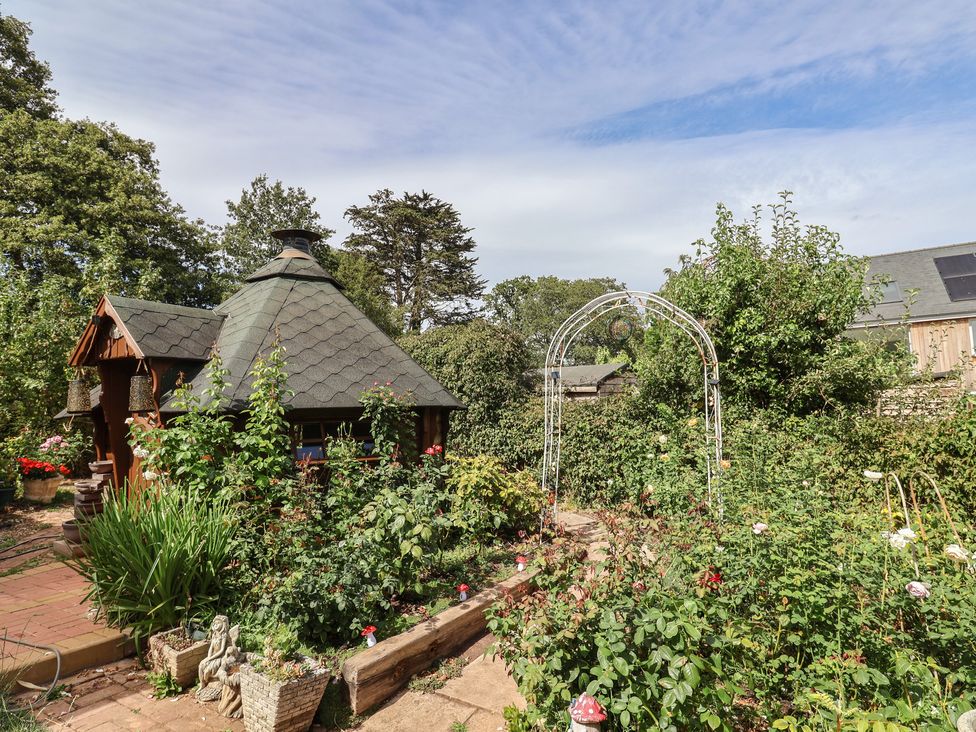 A garden with a shed and flower beds at Mei's Cottage in Pinhoe