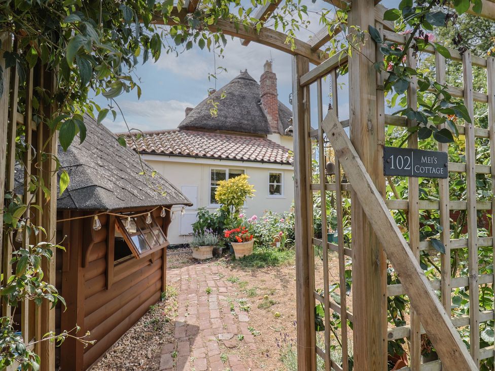 A garden view with a pathway and flower pots at Mei's Cottage in Pinhoe