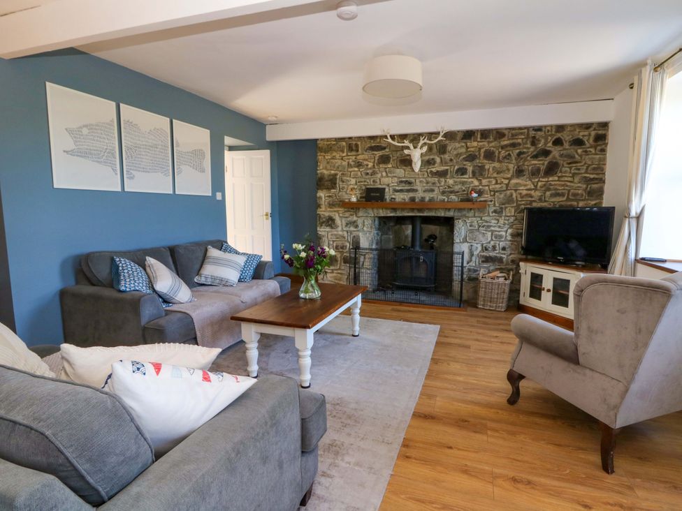 A living room with a stone fireplace a television a wooden coffee table and sofas at Towyn Hall in New Quay