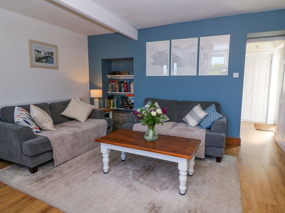 A living room with two gray sofas and a wooden coffee table with flowers on it at Towyn Hall in New Quay