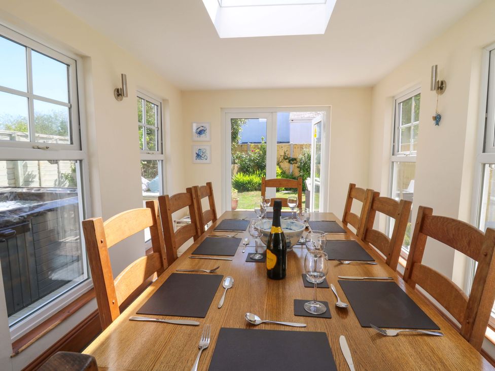 A dining room with a wooden table set with placemats, cutlery, glasses, a bottle, and a bowl at Towyn Hall in New Quay