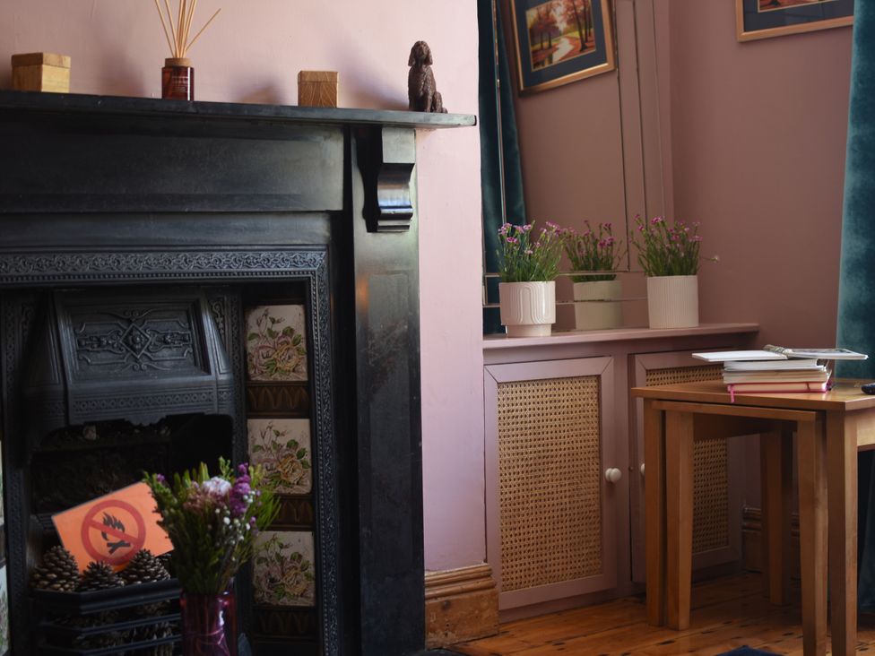 A living room with a fireplace and plants on a cabinet at 33 High Street Fortuneswell