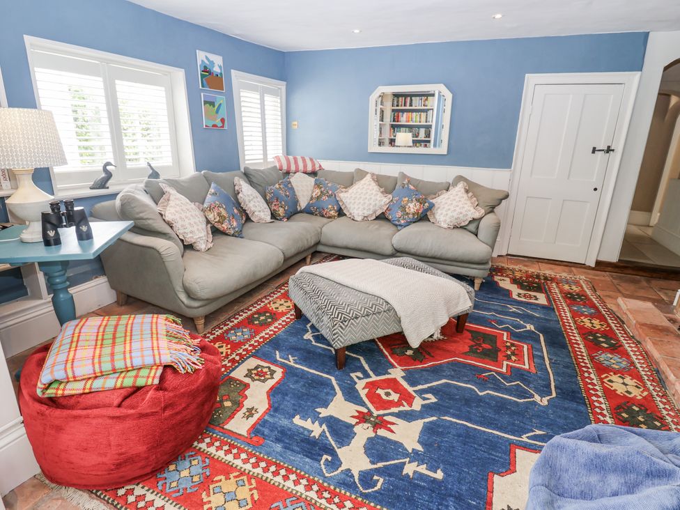 A living room with a sofa and bookshelf at Syleham House in Syleham near Eye