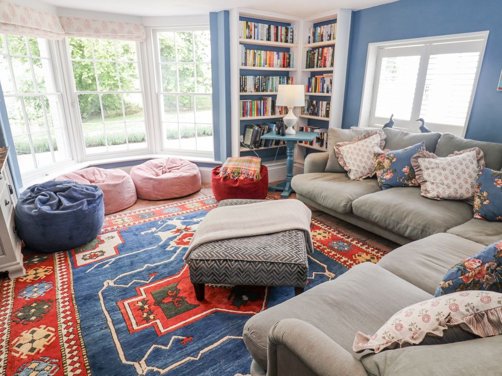 A living room with a sofa, bean bag chairs, and a bookshelf at Syleham House in Syleham near Eye