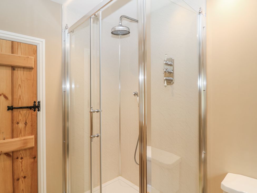 A bathroom with a shower enclosure and wooden door at Syleham House near Eye