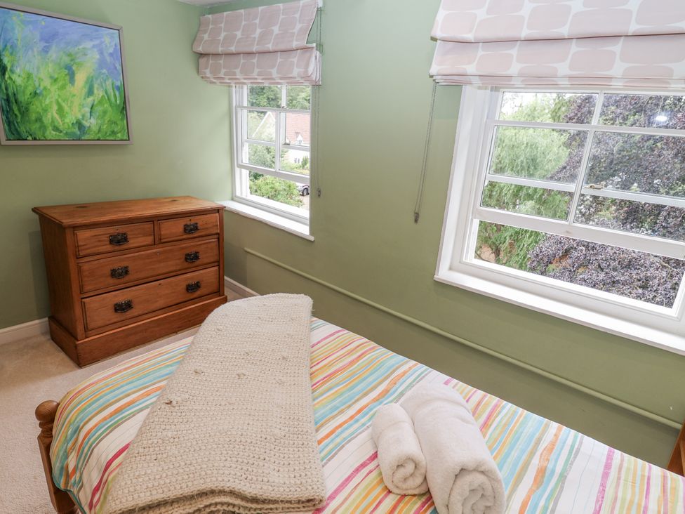 A bedroom with a bed, dresser, and windows at Syleham House in Syleham near Eye