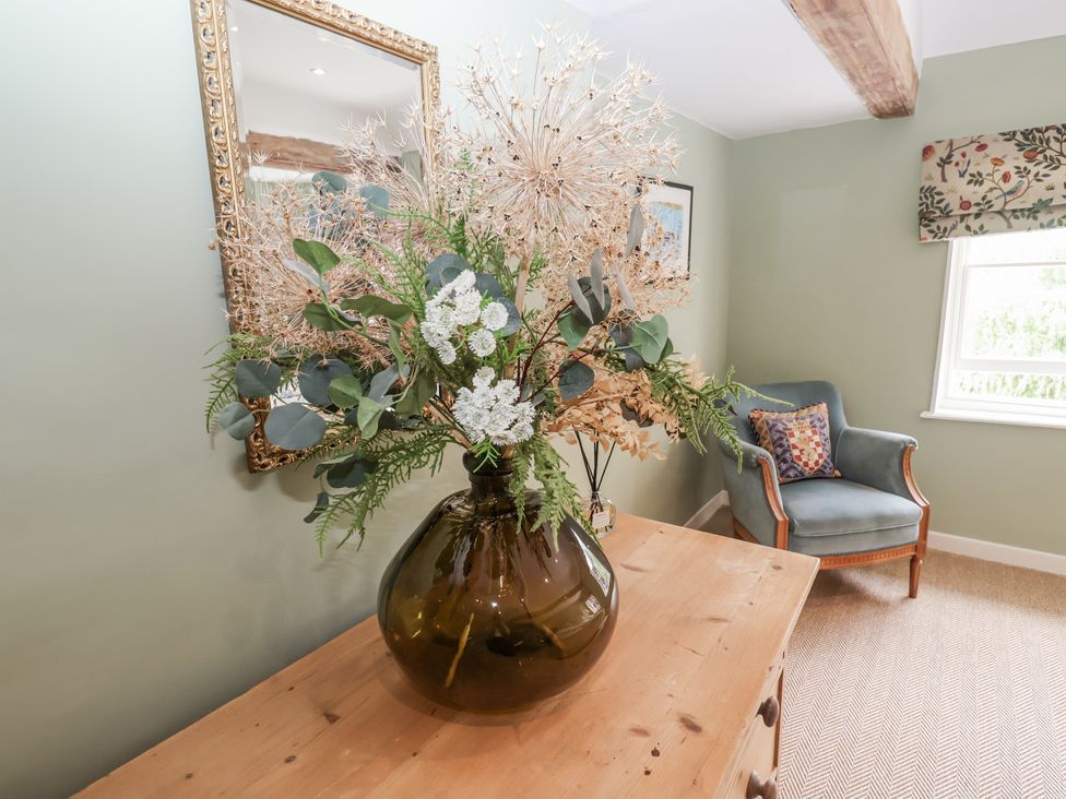 A sitting room with a vase of flowers on a side table at Syleham House near Eye