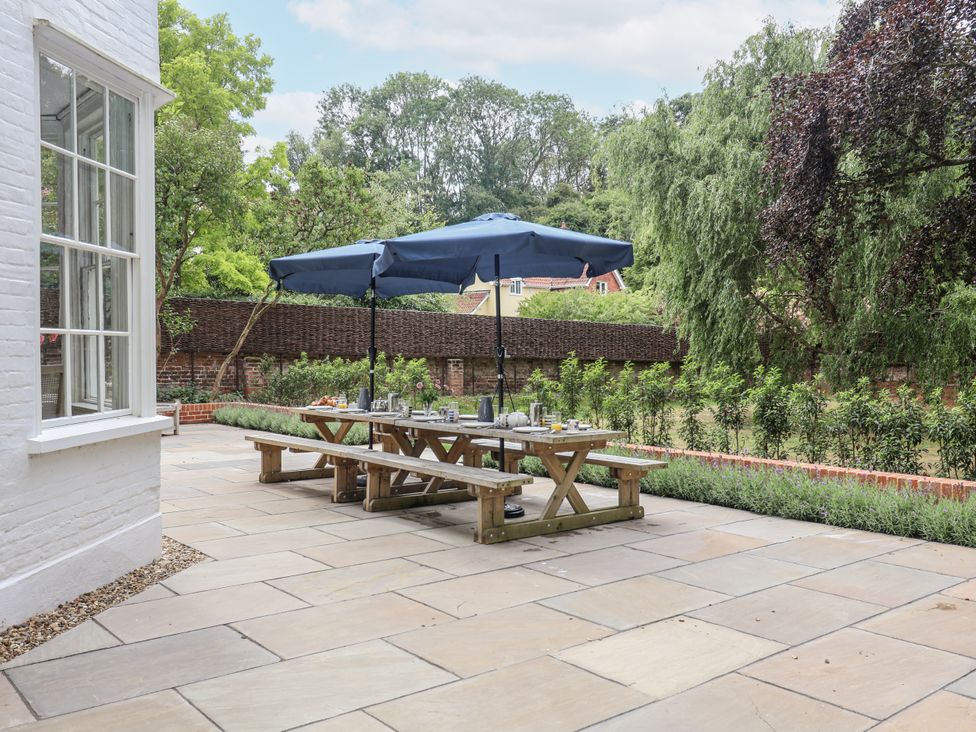 A garden with a table and benches under an umbrella at Syleham House Syleham near Eye