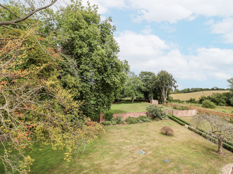A garden with trees and a brick wall at Syleham House Syleham near Eye