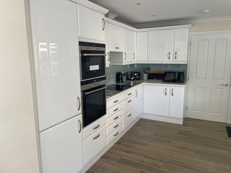 A kitchen with cabinets, oven, microwave, and kettle at 3 Strawberry Close Little Haven near Broad Haven