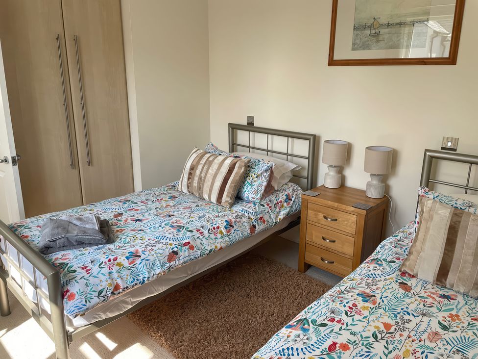 A bedroom with two beds and a bedside table at 3 Strawberry Close Little Haven near Broad Haven