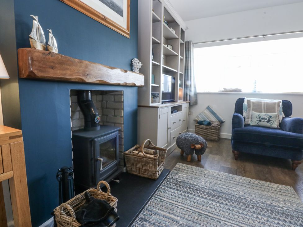 A living room with a fireplace and a blue chair at Bwthyn Y Swnt in Moelfre