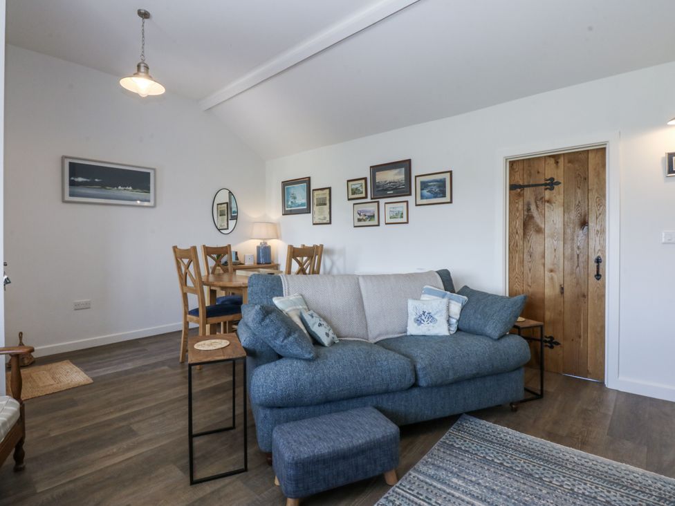A living room with a sofa and dining table at Bwthyn Y Swnt in Moelfre