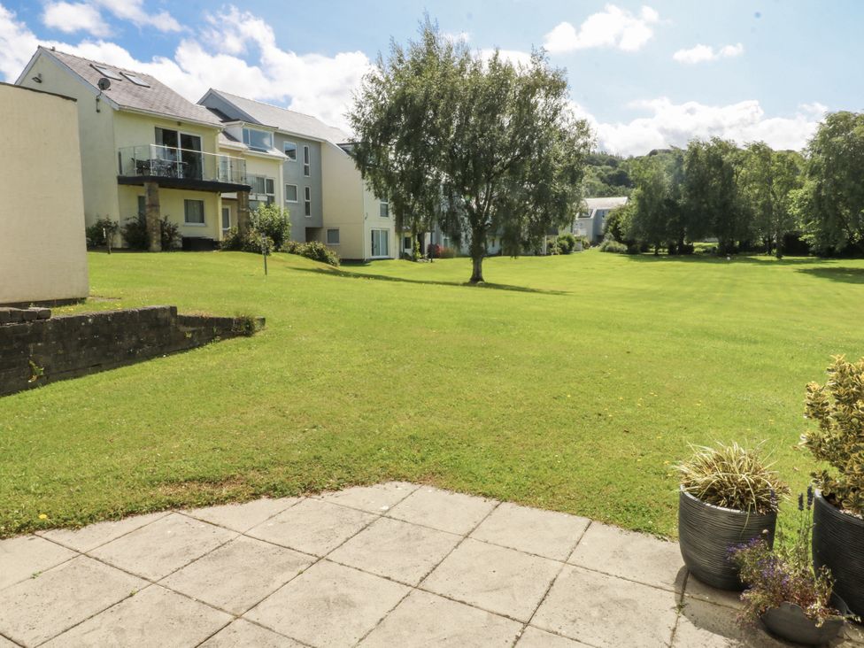 An outdoor area with grass and surrounding buildings at Bwthyn Y Swnt in Moelfre