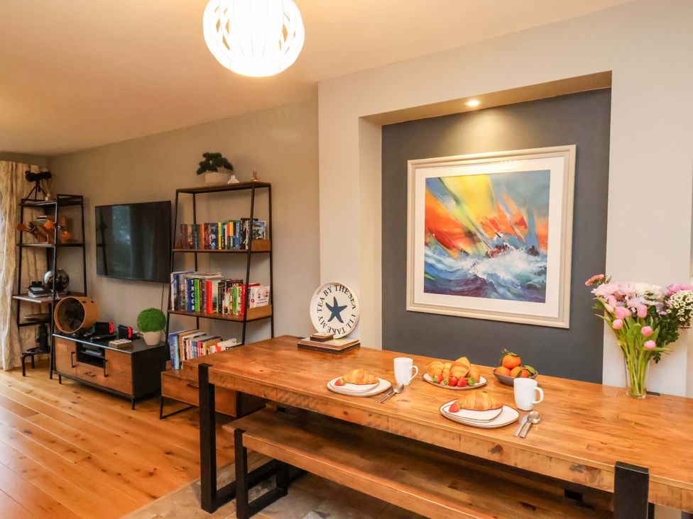 A dining room with a wooden table and television at The Beach Retreat The Bay - Filey