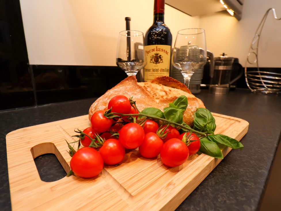 A cutting board with bread tomatoes and wine in a kitchen at The Beach Retreat The Bay - Filey