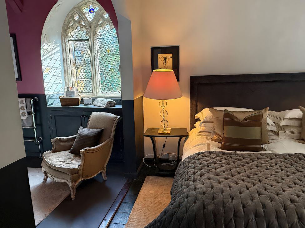 A bedroom with a bed and a chair at King Ina's Palace South Petherton