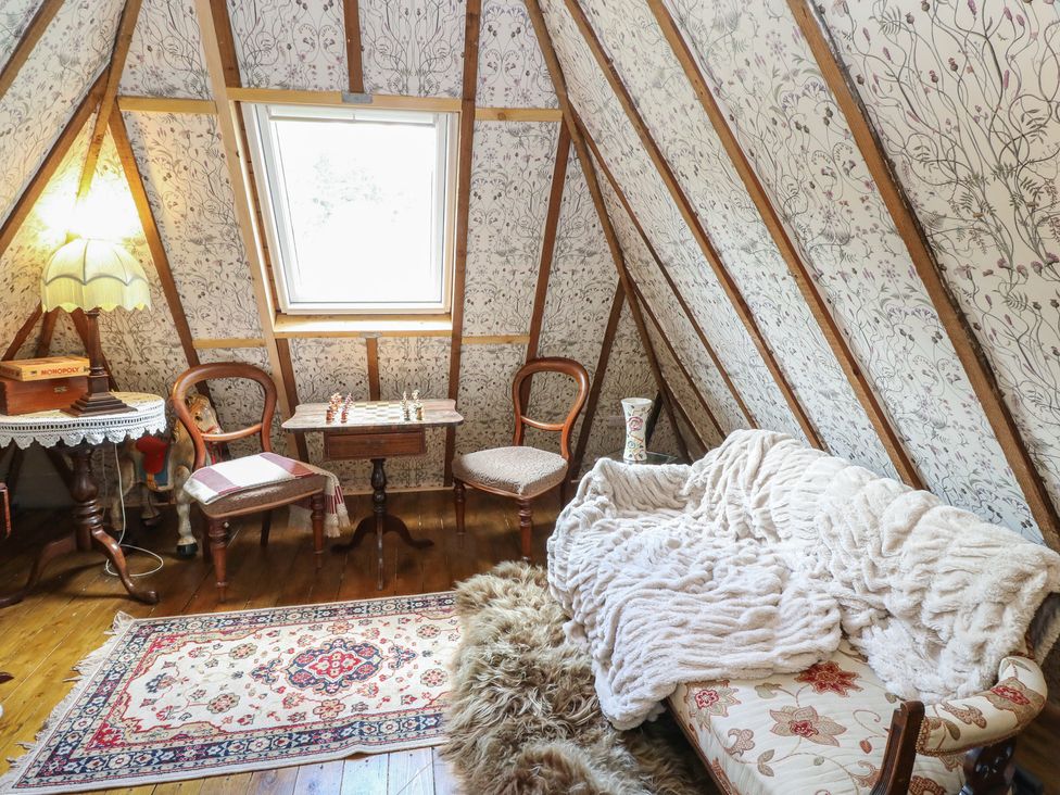 A cozy attic with seating and a table at The Cottage In The Woods, Connel, Argyll & Bute