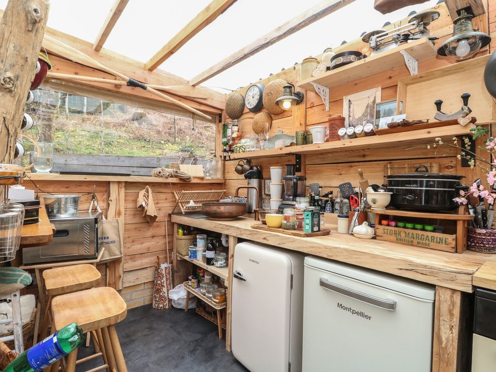 A kitchen with wooden shelves and various kitchen appliances at The Cottage In The Woods Connel, Argyll & Bute