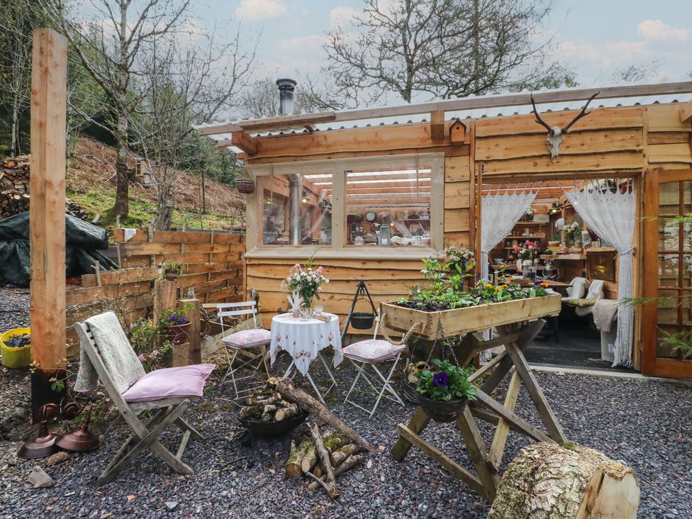 An outdoor area with a wooden building, seating and planters at The Cottage In The Woods, Connel, Argyll & Bute