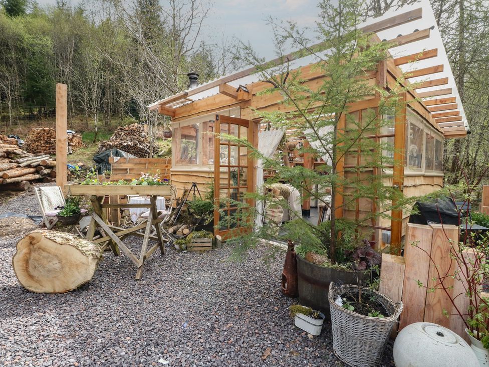 A garden area with wooden structure and table at The Cottage In The Woods, Connel, Argyll & Bute