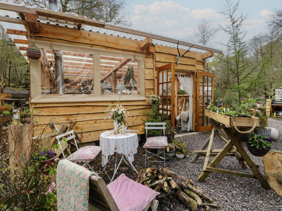 A wooden cabin with a table and chairs in the garden at The Cottage In The Woods, Connel, Argyll & Bute