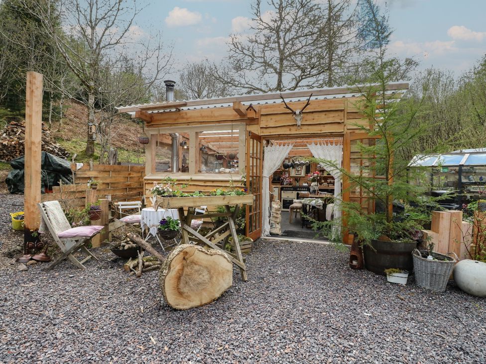 A shed with wooden furniture and plants at The Cottage In The Woods Connel, Argyll & Bute