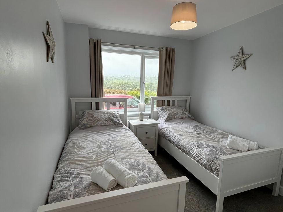 A bedroom with two single beds and a window at Llwyn Eithin in Benllech
