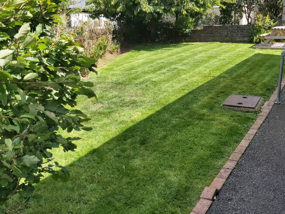 A garden with a lawn and a manhole cover at Llwyn Eithin Benllech