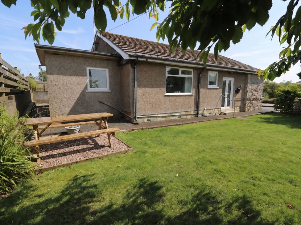 A house with a picnic bench and lawn at Llwyn Eithin in Benllech
