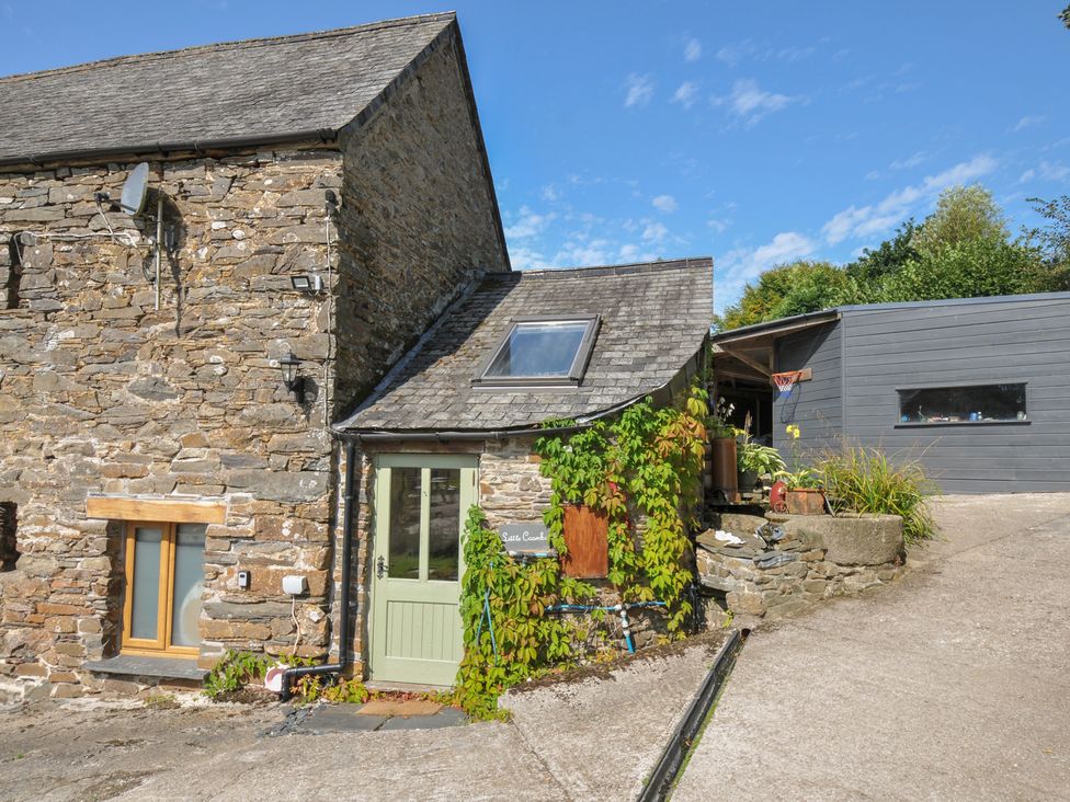 A stone building with a green door and plants at Little Coombe Trehunist near Liskeard
