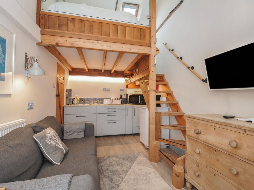 A living room with a kitchenette and staircase at Little Coombe in Trehunist near Liskeard