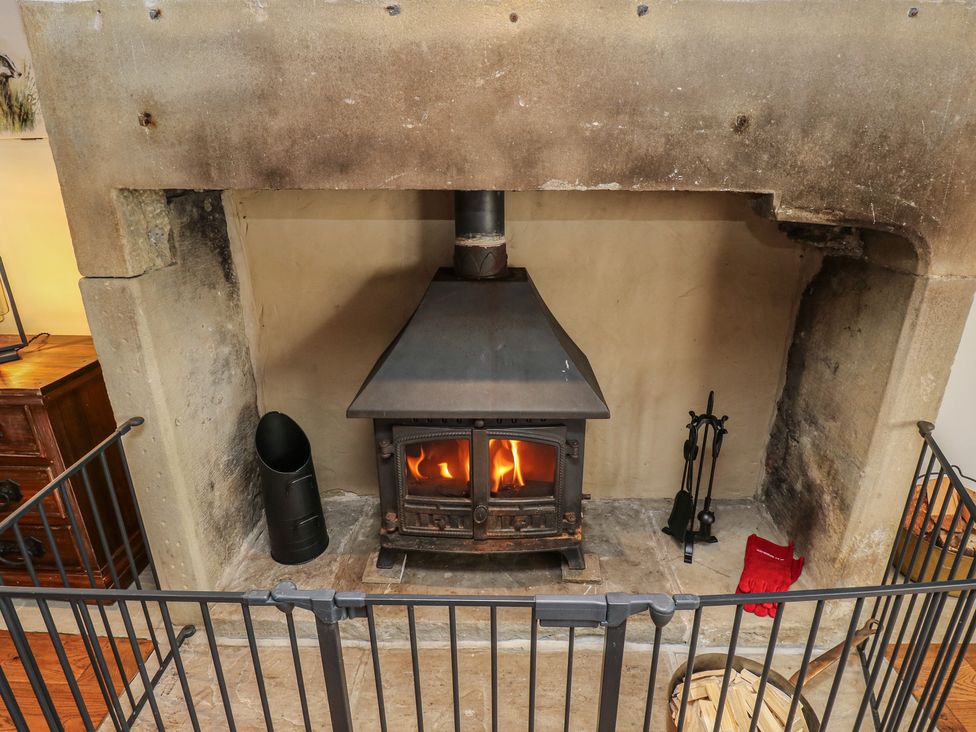 A fireplace with a wood stove and firewood holder at Stagwood House in New Mill