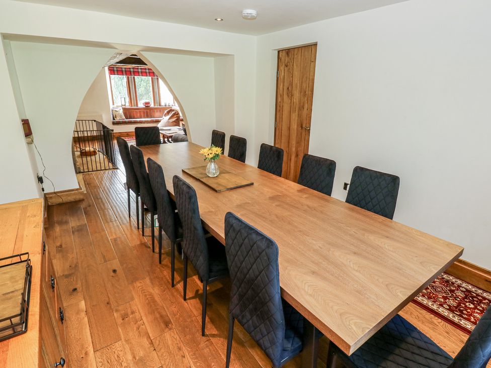 A dining room with a long table and chairs at Stagwood House in New Mill