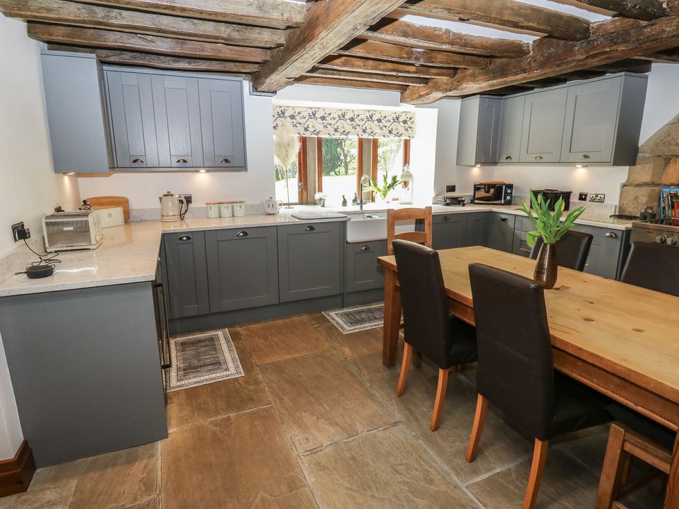 A kitchen with cabinets and a table at Stagwood House in New Mill
