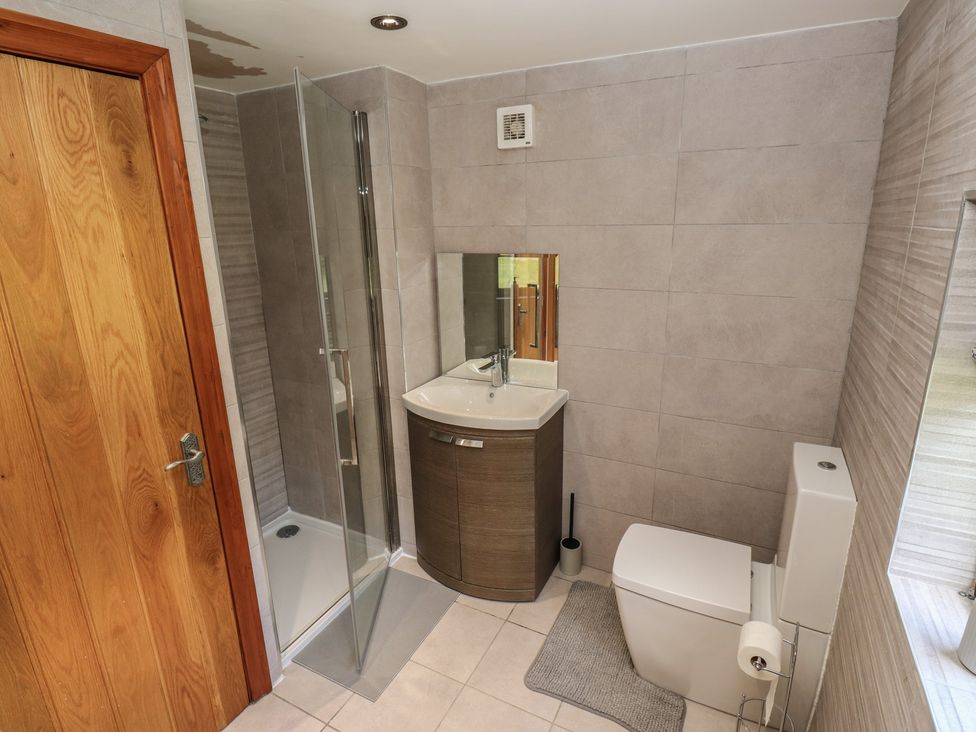 A bathroom with a shower, sink, toilet, and mirror at Stagwood House in New Mill