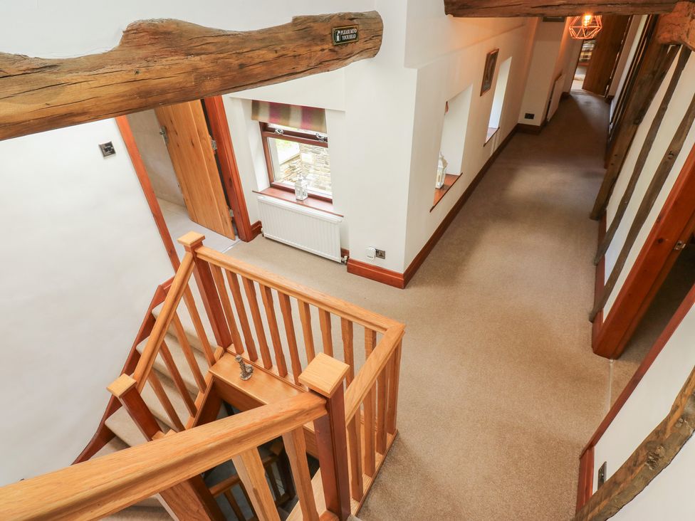 A hallway with a staircase and wooden railing at Stagwood House in New Mill