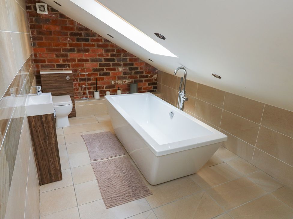 A bathroom with a bathtub, toilet, and sink at Stagwood House in New Mill