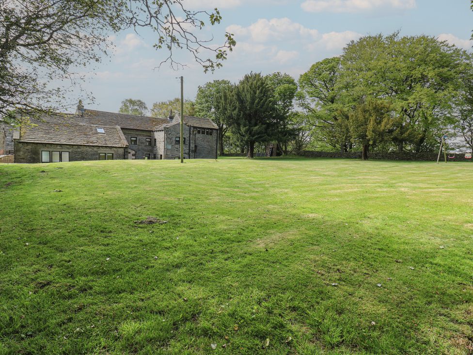 An outdoor area with grass, trees, and a house at Stagwood House in New Mill