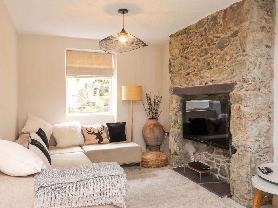 A living room with a sofa, television, and lamp at Hendre in Menai Bridge