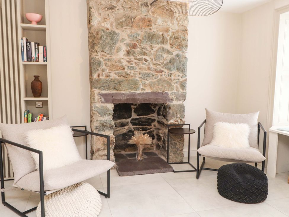 A living room with a fireplace and armchairs at Hendre in Menai Bridge