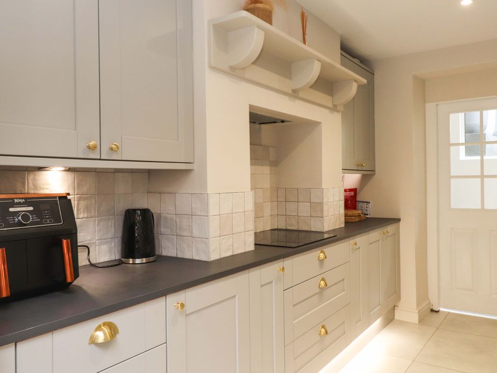 A kitchen with cabinets, appliances, and a door at Hendre in Menai Bridge