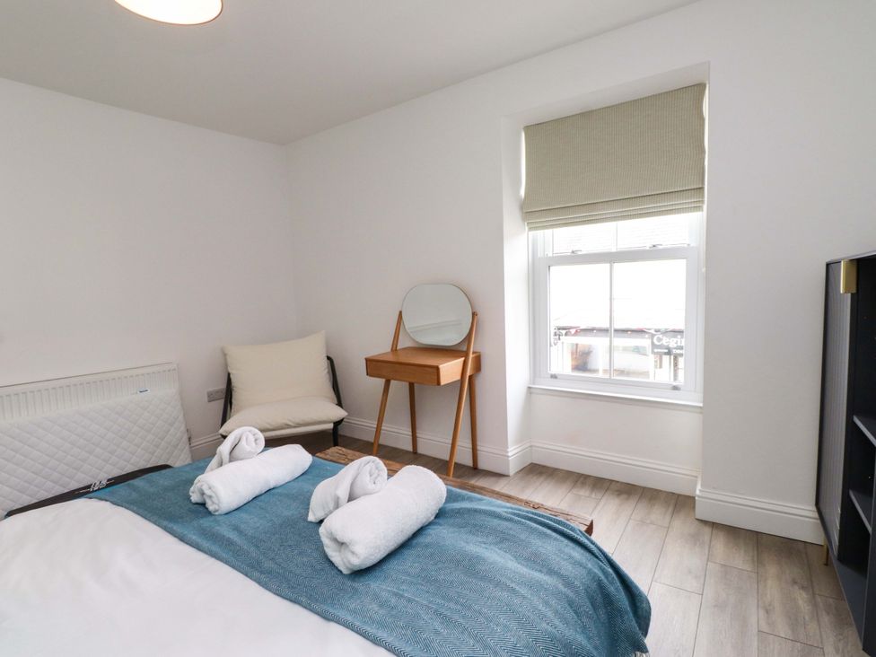 A bedroom with a bed and towels on top at Hendre in Menai Bridge