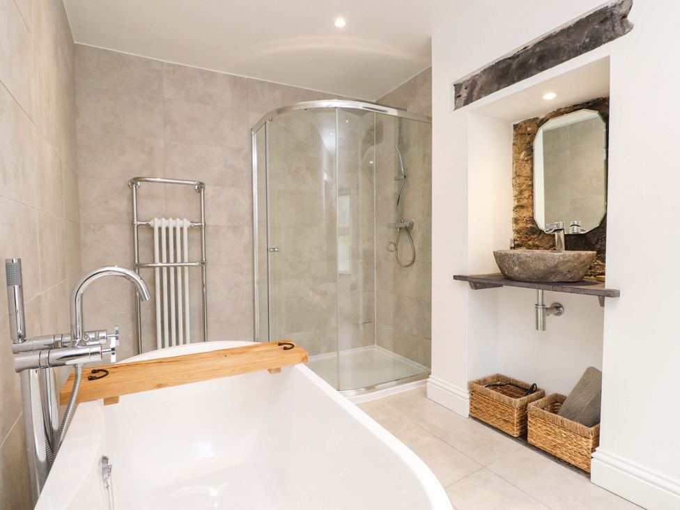 A bathroom with a bathtub, shower, and sink at Hendre in Menai Bridge