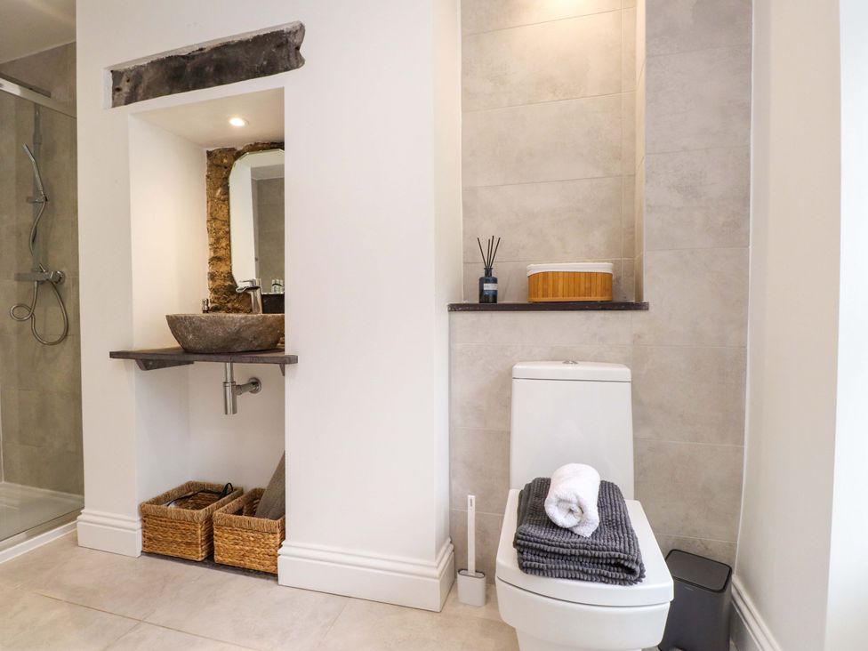 A bathroom with a sink, toilet, and storage baskets at Hendre in Menai Bridge