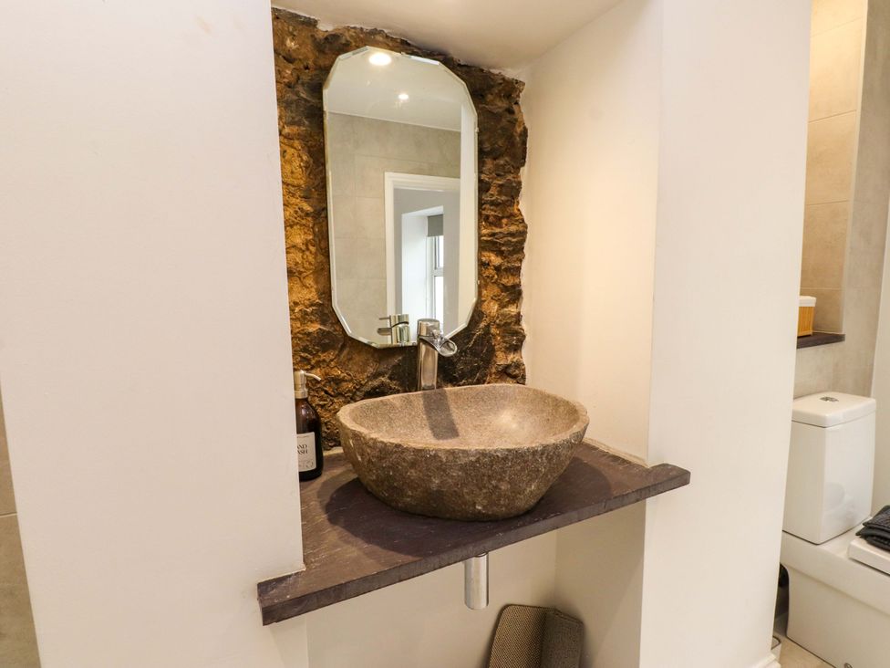 A bathroom with a stone sink and mirror at Hendre in Menai Bridge