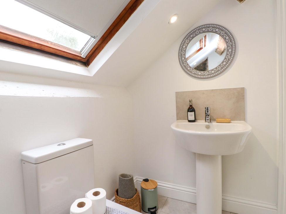 A bathroom with a sink and toilet with a mirror at Hendre in Menai Bridge