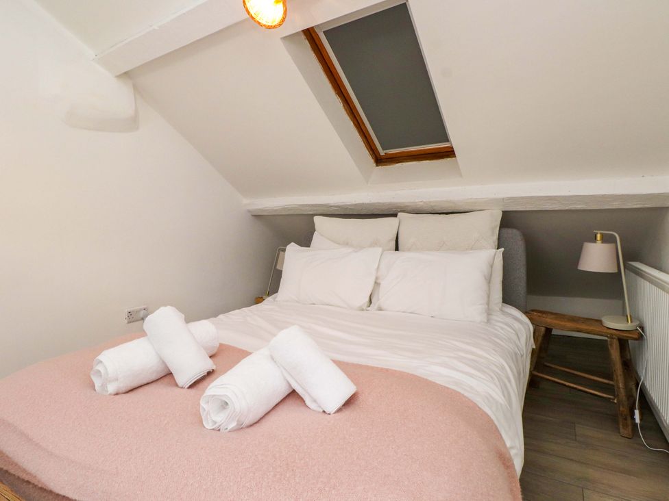 A bedroom with a bed, pillows, and towels at Hendre in Menai Bridge