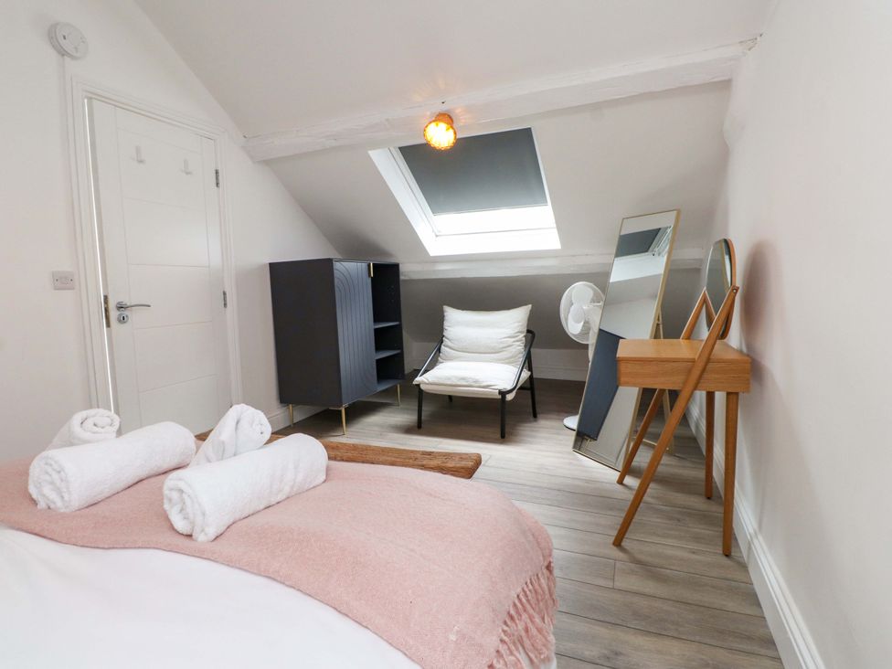 A bedroom with towels on a bed and a chair at Hendre in Menai Bridge
